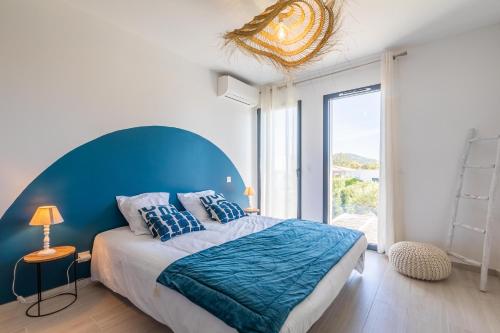 une chambre avec un grand lit avec une tête de lit bleue dans l'établissement Villa Baia T3 - Kids Friendly - Clim - 900m plages St Cyprien & Cala Rossa, à Lecci