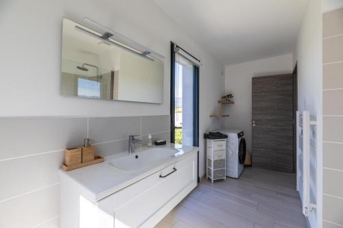 une salle de bain blanche avec un lavabo et un miroir dans l'établissement Villa Baia T3 - Kids Friendly - Clim - 900m plages St Cyprien & Cala Rossa, à Lecci