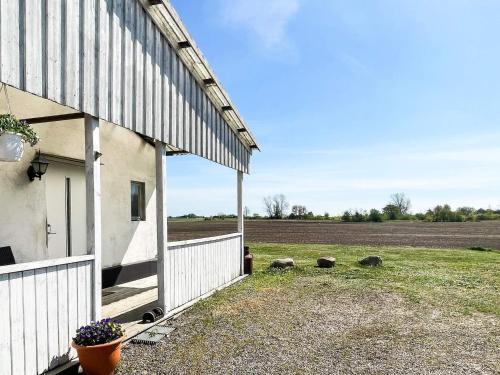 a white barn with a field in the background at 4 person holiday home in ANDERSLÖV in Anderslöv