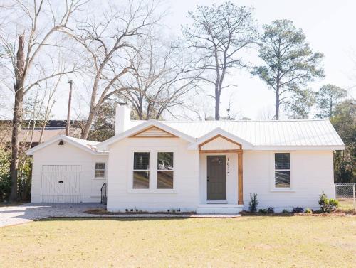 een wit huis met een garage bij Cozy Historic District Cottage in Dothan
