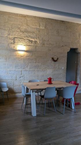 une table et des chaises en bois devant un mur de briques dans l'établissement Appartement de charme au coeur d'Uzès, à Uzès
