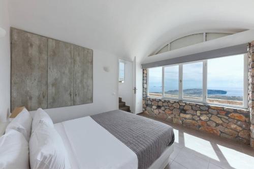 a bedroom with a bed and a large window at Zatrikion Santorini Villas in Pirgos