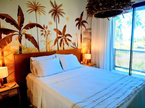 una camera da letto con un grande letto con palme sul muro di Casa Arcanjo - Patacho a Pôrto de Pedras