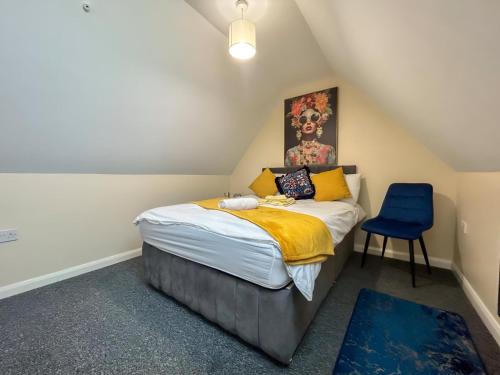 a small bedroom with a bed and a blue chair at Sherry's 2 Bed Guest House in Buckinghamshire
