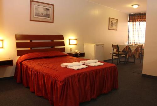 a bedroom with a red bed with two towels on it at Los Mirtos suite & Hotel in Lima