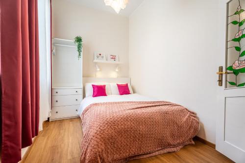 ein kleines Schlafzimmer mit einem Bett mit rosa Kissen in der Unterkunft Sunny Lodging in Sliema
