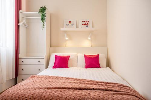 a small bedroom with a bed with pink pillows at Sunny Lodging in Sliema