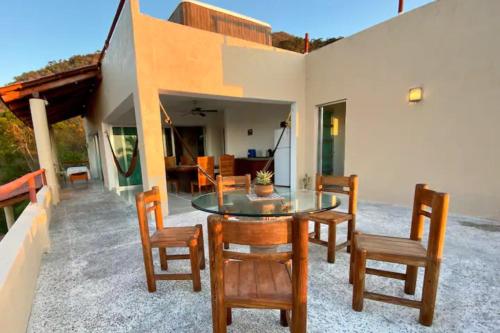 a dining room with a glass table and chairs at Vistas a las Montañas y al Mar I Condominio Las Calandrias I Alberca I Wi-Fi in Ixtapa
