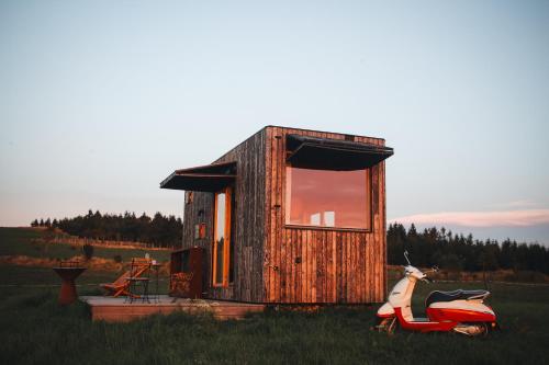 a tiny house with a scooter parked in a field at Glamping Na Malém Háji in Hora Svaté Kateřiny