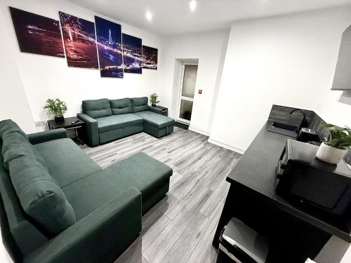 Una sala de estar con un sofá verde y un televisor. en Hornby Hottub and Jacuzzi Suites, en Blackpool