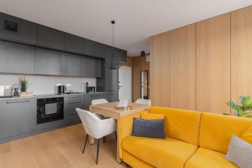 a living room with a yellow couch and a table at Fuzja w Chmurach - parking, klimatyzacja by FuzjaAparts in Łódź