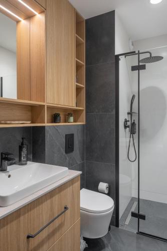 a bathroom with a toilet and a sink and a shower at Fuzja w Chmurach - parking, klimatyzacja by FusionAparts in Łódź