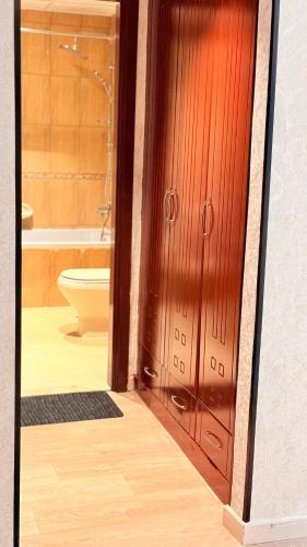 a bathroom with a toilet and a wooden door at BEST PLACE HOLIDAY HOME ii FREE PARKING in Ajman 
