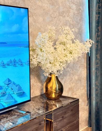 a vase of flowers on a table next to a tv at BEST PLACE HOLIDAY HOME ii FREE PARKING in Ajman 