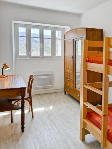a bedroom with bunk beds and a desk and a table at La maison des Hortensias Vic-Sur-Cère, 10 pers in Vic-sur-Cère
