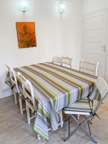 a dining room table with chairs and a striped table cloth at La maison des Hortensias Vic-Sur-Cère, 10 pers in Vic-sur-Cère
