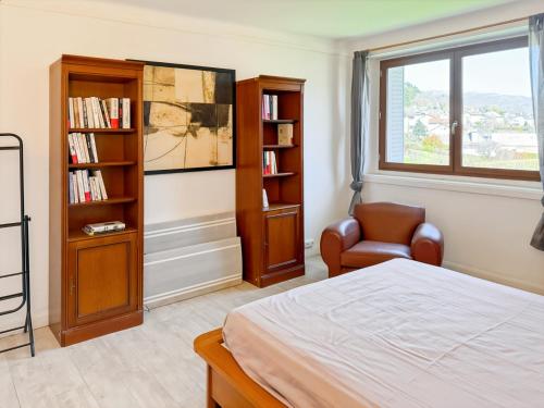 a bedroom with a bed and a chair and a book shelf at La maison des Hortensias Vic-Sur-Cère, 10 pers in Vic-sur-Cère