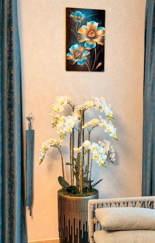 a vase of flowers on a wall with a picture at BEST PLACE HOLIDAY HOME ii FREE PARKING in Ajman 