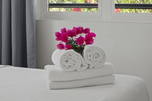 a white vase filled with pink flowers on top of towels at Villa Monte Azul in Willemstad