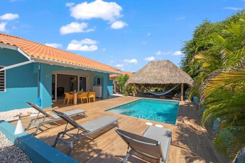 a villa with a swimming pool and chairs and a house at Villa Monte Azul in Willemstad