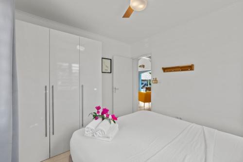 a white bedroom with a white bed with pink flowers at Villa Monte Azul in Willemstad