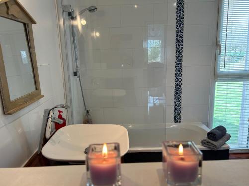 two candles on a counter in a bathroom with a tub at La Chambre de Kerly in Pléguien