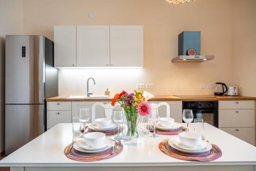 a kitchen with a table with plates and flowers on it at Sunny Lodging in Sliema