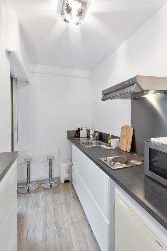 une cuisine avec comptoirs blancs et appareils en acier inoxydable dans l'établissement Le Majestic - Hypercentre - Croisette - AC, à Cannes