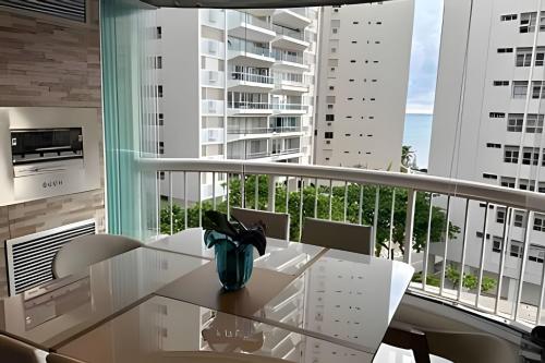 een wit balkon met een tafel en stoelen en een groot raam bij Flat ao lado do Mar Four Season in Guarujá