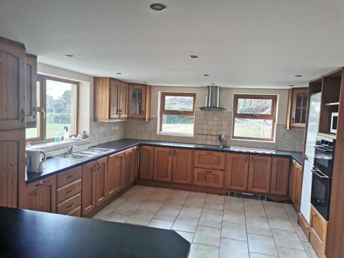 a kitchen with wooden cabinets and black counter tops at Beacon View, Church Cross, Skibbereen, County Cork in Church Cross