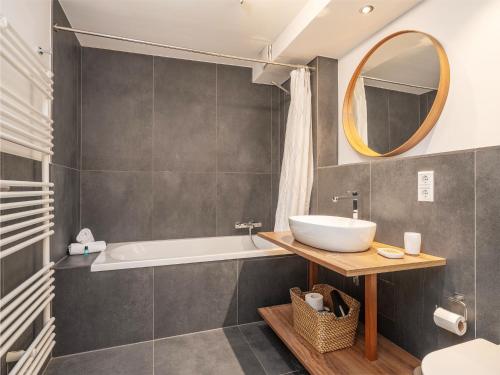 een badkamer met een wastafel, een bad en een spiegel bij Moderne stilvolle Wohnung im Herzen Münchens in München
