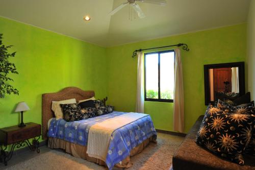 a bedroom with green walls and a bed and a window at Villa Langosta by Cabo Villas in La Paz