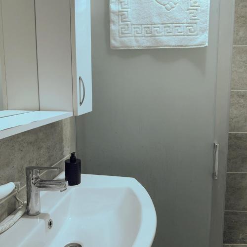 a bathroom with a white sink and a mirror at Hera Pansiyon in Ayvalık