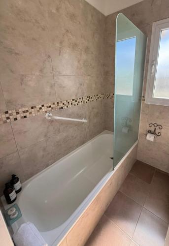 a bathroom with a tub and a glass shower at Apart Boutique Macedonia in San Lorenzo