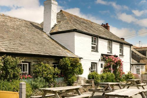 a white building with picnic tables in front of it at Shepherds Huts at The Cornish Arms in Saint Merryn
