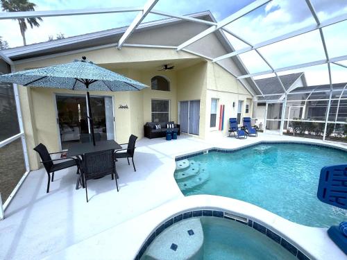 a pool with a table and chairs and an umbrella at Beautiful South-Facing Pool Home in Southern Dunes in Haines City