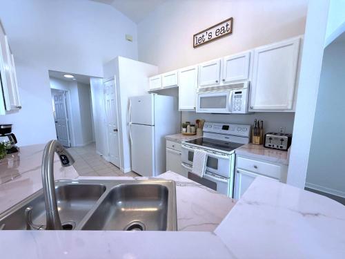 a kitchen with white appliances and a sign that reads last call at Beautiful South-Facing Pool Home in Southern Dunes in Haines City