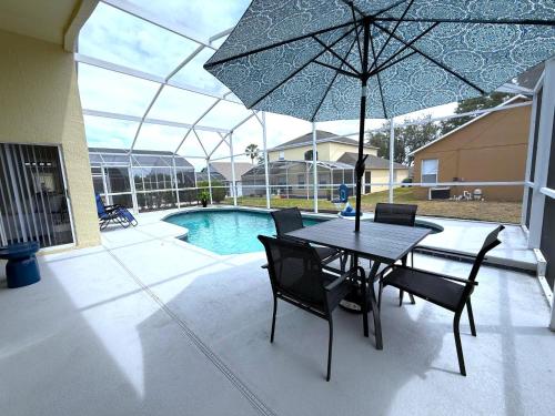 a table and chairs with an umbrella and a pool at Beautiful South-Facing Pool Home in Southern Dunes in Haines City
