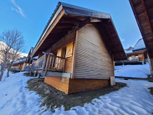 a log cabin with a deck in the snow at Chalet 6 à 8pers pied des pistes, piscine et vue in Saint-François-Longchamp