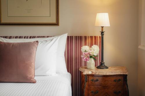 a bedroom with a bed and a table with a lamp at The Russell Boutique Hotel in Sydney