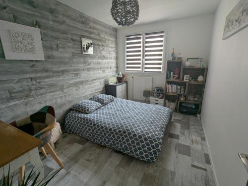 une chambre avec un lit et un mur en bois dans l'établissement Appartement idéal circuit des 24h du Mans, au Mans