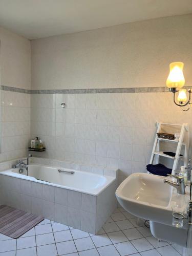 une salle de bain blanche avec une baignoire et un lavabo dans l'établissement Demeure des Payratons, à Saint-Gérand-le-Puy