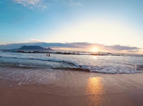 two people standing in the water at the beach at Our Cape Town Home - Beach Villa with Stunning Sea & Mountain Views! in Bloubergstrand