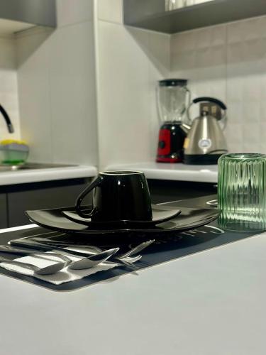 a black coffee cup on a plate on a kitchen counter at Lindo y central departamento in Chillán