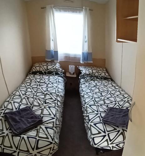 two beds in a small room with a window at The cosy getaway in Selsey