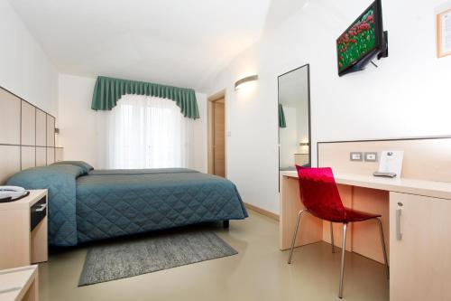 Schlafzimmer mit einem Bett, einem Schreibtisch und einem roten Stuhl in der Unterkunft Hotel Miorelli in Nago-Torbole