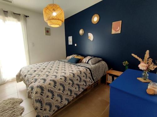 une chambre avec un lit et un mur bleu dans l'établissement Maison Ranoa, à Saint-Jean-de-Ceyrargues