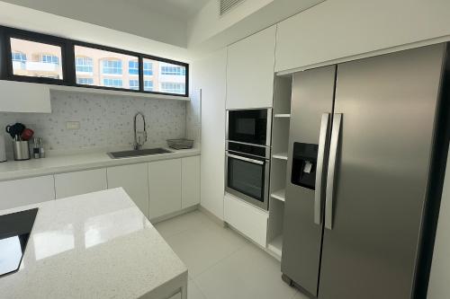 a kitchen with a stainless steel refrigerator and white cabinets at Espectacular apartamento en Playa El Angel ALAQUA 2000 in Pampatar