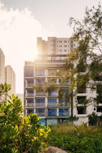 a tall building with the sun shining on it at Lazzlla Beachfront Oceanfront Apartments in Hulhumale
