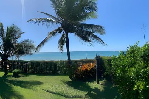 a palm tree in a yard with the ocean in the background at Casa das Palmeiras (Pé na Areia) - Maré Verde in Rio das Ostras